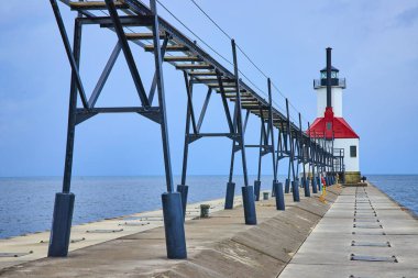 Stunning view of Benton Harbors Inner Lighthouse on Lake Michigan, standing tall at the end of a tranquil pier. The clear sky and calm water enhance the serene atmosphere, perfect for reflecting clipart