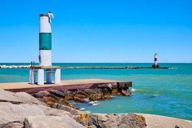 Wisconsin, Kenosha 'daki Michigans Gölü' nün kayalık kıyılarında iki ikonik deniz feneriyle sakin sahil manzarası. Ön planda beyaz ve yeşil işaret, uzakta kırmızı ve beyaz işaret. İdeal