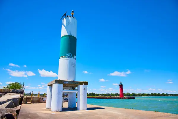 stock image Vibrant lakeside scene featuring a green and white navigational aid tower and a red lighthouse in Kenosha, Wisconsin. The serene blue-green waters of Lake Michigan reflect the clear sky on a bright