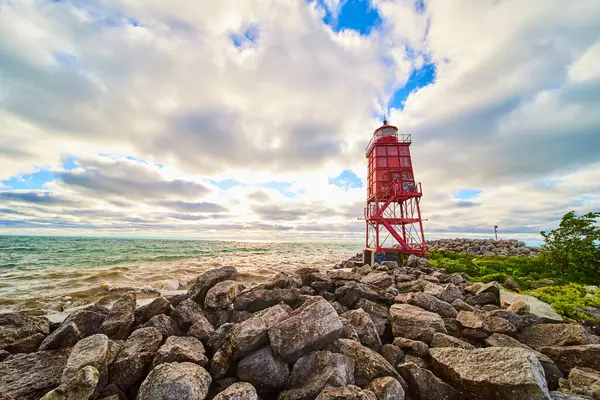 stock image Racine Breakwater Lighthouse stands resilient on the rocky shores of Lake Michigan at sunrise. This Wisconsin coastal scene captures the harmony between bold industrial design and serene natural