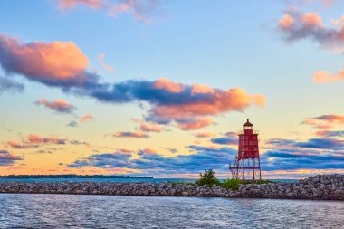 Wisconsin 'deki Michigan Gölü' ndeki Racine Breakwater Deniz Feneri 'nde sakin bir şafak. Kırmızı deniz feneri kayalık dalgakıranın üzerinde duruyor, güneşin sıcacık renkleriyle yıkanmış, sükuneti ve doğayı çağrıştırıyor.