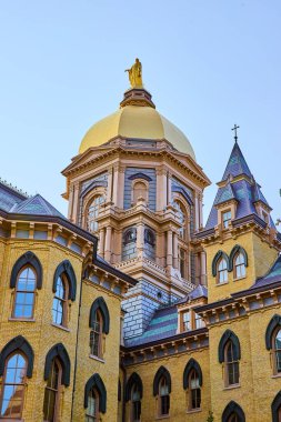 Notre Dame Üniversitesi 'ndeki Altın Kubbe, Gotik ve Rönesans mimarisini sergileyen açık mavi gökyüzünün altında parıldıyor. Gelenek ve akademi temaları için mükemmel.