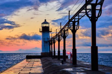 St. Joseph North Pier, Benton Limanı 'nda altın saat: Michigan Gölü üzerinde canlı turuncu, pembe ve mor bir gökyüzüne karşı durmakta olan sakin bir deniz feneri. Huzur, rehberlik ve rehberlik temaları için mükemmel.