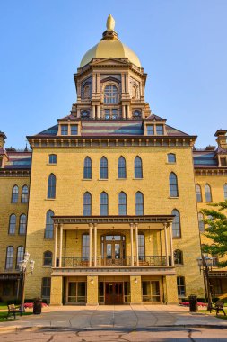 Notre Dame 'ın altın kubbesi altın saatinde parlayarak neoklasik ve romantik mimarisini sergiliyor. Patikaları, bankları ve klasik lambaları olan sakin kampüs sahnesi.