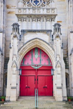 The grand entrance of First Presbyterian Church in downtown Kalamazoo, Michigan. Featuring Gothic-style architecture with vibrant red doors and ornate ironwork, this historic landmark exudes elegance clipart