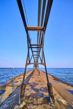 Benton Harbors North Pier extends into Lake Michigan under a clear sky, showcasing industrial elegance with its metal framework. A lighthouse stands in the background, highlighting maritime heritage clipart