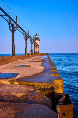 Michigan Gölü 'ndeki Benton Limanı Kuzey İskelesi Deniz Feneri' nde altın saat. Issız bir figür iskelede yürüyor, sakin gündoğumunun ışıltısında güneşleniyor. Huzur, yalnızlık ve sahil temaları için mükemmel.