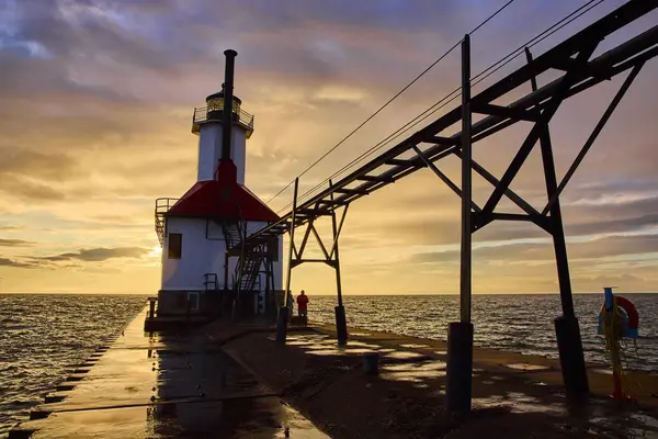 stock image Serene sunset at Benton Harbor Inner Lighthouse, St. Joseph, Michigan. The tranquil scene features a lone figure on the pier, reflecting the peaceful golden hour by Lake Michigan.