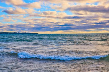 Racine, Wisconsin 'deki Michigan Gölü' nün üzerinde gün doğumu yumuşak dalgalar ve sakin bir kıyı şeridi üzerine sıcak bir ışık saçıyor. Bu deniz manzarasının sakin güzelliğini dramatik bir gökyüzü ve uzak bir yer ile tecrübe edin.