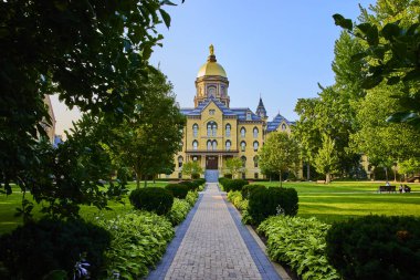 Notre Dame Üniversitesi 'nin ikonik ana binası berrak mavi gökyüzünün altında parıldayan altın kubbesi, yemyeşil ve titizlikle korunan bahçeleri, akademik coşkuyla doludur.