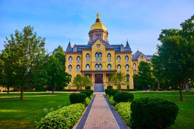 Notre Dame Üniversitesi 'nin ikonik altın kubbesinin Tanrı Avlusu, South Bend' deki tarihi binasının muhteşem manzarası. Büyük mimari ve verimli yeşillik kampüsün prestijini ön plana çıkarıyor.