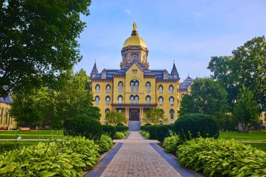 Parlak altın kubbesi olan tarihi üniversite binası, yemyeşil bahçeler ve olgun ağaçlarla çevrili. South Bend, Indiana 'daki Notre Dame' da Tanrı Avlusu 'nun huzurlu ve prestijli atmosferini yakalar..