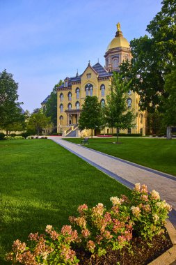 Notre Dame Üniversitesi, South Bend 'in tarihi ana binasının tepesinde görkemli bir altın kubbe. Manikürlü çimenler ve çiçek açan çiçeklerle çevrili bu sakin kampüs sahnesi akademik ihtişamı ve