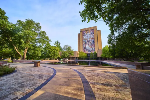 stock image Notre Dame Hesburgh Library with the iconic Word of Life mural Touchdown Jesus. Lush greenery and a serene reflecting pool create a tranquil scene on this historic Indiana campus.