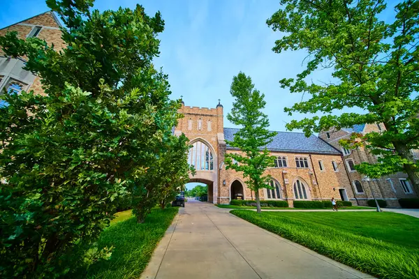 stock image Gothic Revival architecture at the University of Notre Dame in South Bend, Indiana. Elegant arched gateway, intricate detailing, and tranquil landscaped gardens create a serene and historic campus