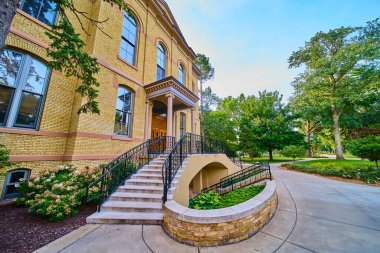 South Bend 'deki Notre Dame Üniversitesi' nin yemyeşil kampüsünde görkemli sarı tuğlalı bir bina ve klasik sütunlar. Manikürlü bahçelerden geçen davetkar bir patika,