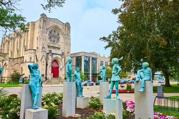 stock image Bronson Park in Kalamazoo showcases the Gothic-style First Presbyterian Church with its stunning rose window and red doors, surrounded by vibrant flowers and playful statues, blending history and