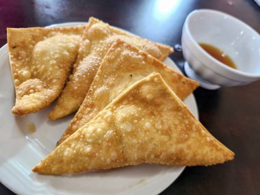 Samimi bir restoranda parlak bir masaya serilmiş, keskin soslu, beyaz bir tabakta altın-kahverengi samosalar. Fort Wayne, Indiana 'da Hint mutfağı ve konforlu yemekler sergilemek için mükemmel..