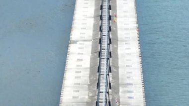 Havadan Tilt Shot: Michigan 'daki St. Joseph Deniz Feneri ve İskelesi' nin dingin güzelliğini tecrübe edin, insanlar iskelede geziniyor, Michigan Gölü 'nün canlı arka planına karşı kuruluyorlar. Mükemmel.
