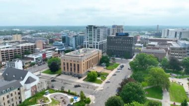 Bronson Park, Comerica Bank binası ve parçalı bulutlu gökyüzü altında tarihi ve modern mimarinin bir karışımının yer aldığı Kalamazoo, Michigan şehir merkezinin havadan izleme çekimi. Canlı şehir ve yeşil