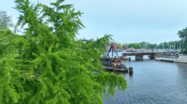 Michigan 'daki tarihi St. Joseph Swing Köprüsü' nün havadan çekilmiş görüntüleri yemyeşil yeşil liman binaları ve sakin gökyüzü altındaki teknelerle sakin bir su geçidine yayılıyor.