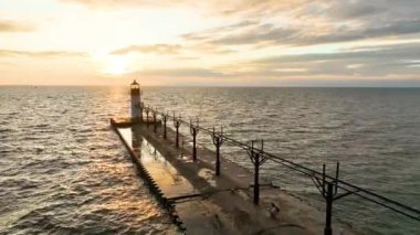 Hava Yolundan İleri Uç Michigan 'daki sakin St. Joseph deniz fenerini gün batımında yakalıyor. Altın parıltı rıhtımda ve deniz fenerinde yıkanır, bu huzurlu güzelliğin ve tarihi cazibenin altını çizer.