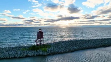 Wisconsin 'deki Michigan Gölü' ndeki Racine Breakwater Deniz Feneri 'nin üzerinde çarpıcı bir gün doğumu. Altın ışınlar, kırmızı deniz fenerini ve kayalık dalgakıranı aydınlatır.