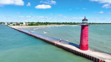 Wisconsin 'deki bir rıhtımda dimdik duran Kenosha Deniz Feneri' nin hava manzarası Michigan Gölü 'nün canlı mavi-yeşil sularıyla çevrili. Parlak gökyüzü ve dingin manzara huzurlu ve davetkar bir ortam yaratır.