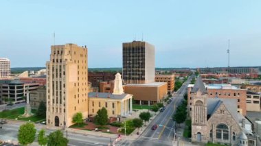 İleriye Uçan Hava: South Bend, Indiana şehir merkezinin büyüleyici günbatımı görüntüsü, St. Joseph Küçük Talep Mahkemesi, modern ofis binaları ve yemyeşil suların ortasındaki tarihi kiliseler