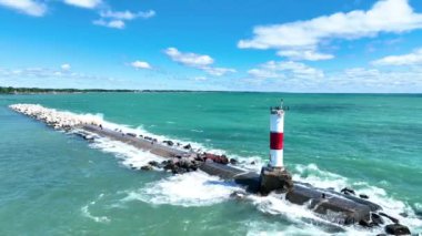 Wisconsin 'deki Kenosha Deniz Feneri' nin Hava Sabit Çekimi. İkonik kırmızı ve beyaz yapı Michigans Gölü 'nün turkuaz sularına karşı dimdik ayakta duruyor. Kayalık iskeleye dalgalar çarpıyor.