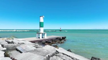 Michigan Gölü 'ndeki Kenosha Deniz Feneri' nin sakin manzarası. Açık mavi gökyüzünün altında kayalık dalgalar üzerinde canlı yeşil ve beyaz bir yapı Kenoshas 'ın sakin güzelliğini yakalar.