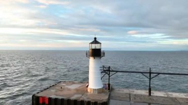 St. Joseph, Michigan 'daki beton bir iskelede sersemletici bir deniz feneri, Michigan Gölü' nün geniş ve sakin sularıyla çevrili, altın gün batımı ışığı ile yıkandı..