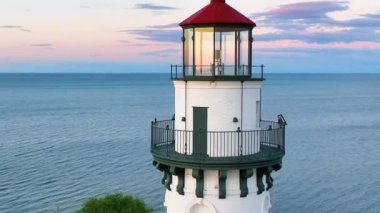 Günbatımında Wisconsin, Racine 'deki Windpoint Deniz Feneri' nin Hava Yayı Çekimi. Kırmızı çatılı beyaz tuğlalı deniz feneri Michigan Gölü 'ne karşı dimdik ayakta duruyor. Çerçevesi yemyeşil ve...