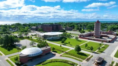 Aerial Arc Shot: Iconic SC Johnson Headquarters in Racine, Wisconsin, designed by Frank Lloyd Wright. Showcases the Research Tower, circular Administration Building, and lush green spaces under a