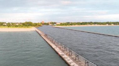 St. Joseph Deniz Feneri, Michigan üzerinde sakin bir günbatımı. İkonik kırmızı çatı ve iskelede beyaz cephe, yemyeşil ve kumlu plajlarla çevrili. Sükuneti yakalayın