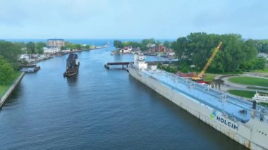 Havadan Uçarak İlerleme: Michigan 'daki hareketli St. Joseph Nehri' ni kargo gemisi Holcim 'in verimli yeşillikleri, tarihi bir demiryolu köprüsünü ve açık havada canlı bir marinayı geçmesiyle tecrübe edin.