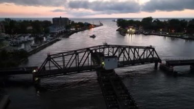 Michigan 'da alacakaranlıkta St. Joseph Swing Köprüsü' nün havadan çekimleri sakin sulardaki tekneler ve parıldayan şehir ışıklarıyla sakin ve sakin bir sahne yaratarak sakin bir altın saati vurguluyor..