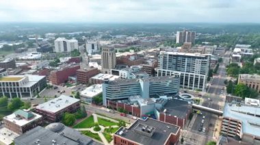 Kalamazoo, Michigan şehir merkezinin hava yayı çekimi, çarpıcı bir modern bina, yemyeşil bir park ve hareketli caddeler sergileniyor. Tarihi ve modern mimarinin karışımı şehirleri vurguluyor