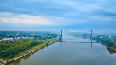 Toledo Ohio 'daki sakin Maumee Nehri' ni kaplayan Anthony Wayne Köprüsü 'nün sakin hava manzarası. Puslu çevre ve bereketli yeşillik kentsel yaşam ve doğa arasında sakin bir bağ oluşturur..