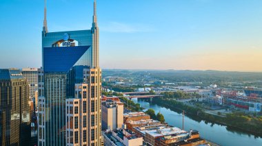 Nashville 'in altın saatindeki gökyüzü manzarası. Simgesel ATT Batman Binası, hareketli gökdelenler ve Cumberland Nehri. Nissan Stadyumu şehrin canlı kültürünü ön plana çıkarıyor..