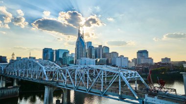 Nashville 'deki altın saat ikonik Batman Binası ve John Seigenthaler Yaya Köprüsü' nü gözler önüne seriyor. Hava manzarası canlı ufuk çizgisini yakalar ve nehir kenarındaki huzur parıltısını. Mükemmel şehir cazibesi.