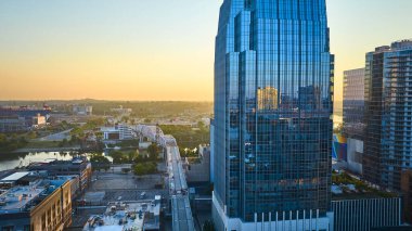 Güneşin doğuşuyla birlikte Nashville 'in canlı ufuk çizgisinin havadan görünüşü, parıldayan cam bir gökdelen ve sakin bir nehrin üzerinde resim gibi bir köprü, şehirlerin modern ve huzurlu özünü yakalıyor..