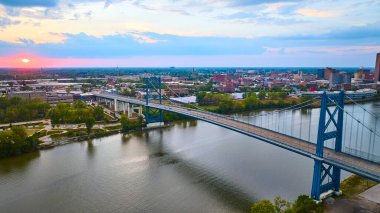 Ohio, Toledo 'nun altın saatindeki çarpıcı hava manzarası. Anthony Wayne Köprüsü, sakin Maumee Nehri boyunca uzanır ve kentsel bağlantıyı ve sakin günbatımı yansımalarını vurgular. Kentsel gelişim için mükemmel