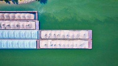 Kum taşıyan üç paralel mavnayla Nashville yeşil nehrinin havadan görünüşü, Tennessee taşımacılık endüstrisindeki endüstriyel lojistik ve sakin su yollarının verimliliğini gösteriyor..