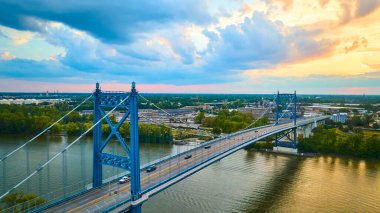Gün batımında Toledo Ohio 'daki Anthony Wayne Köprüsü' nün hava görüntüsü. Çarpıcı mavi kuleler Maumee Nehri boyunca uzanır, altın saat boyunca kentsel ve doğal manzaraları birbirine bağlar..