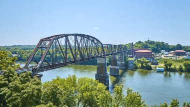 Nashville, Tennessee 'deki tarihi kırmızı tuğla binaların yakınlarındaki yemyeşil manzaraları birbirine bağlayan paslı bir nehir üzerindeki demiryolu köprüsünün havadan görüntüsü. Endüstriyel miras temaları için mükemmel.