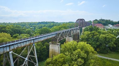Nashville, Tennessee 'de yemyeşil ormanları kaplayan tarihi bir demiryolu köprüsünün havadan görünüşü. Bu paslı çelik yapı, sakin kırsal alanların ortasındaki sanayi mirasını vurguluyor..