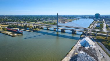Maumee Nehri 'ni kaplayan Toledo Gazileri Cam Şehir Skyway Köprüsü' nün havadan görüntüsü. Güneşli Ohio 'da çarpıcı bir kargo gemisi ve endüstriyel manzarayla canlı deniz ticaretini ön plana çıkarıyor..