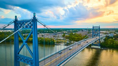 Toledo Ohio 'daki Maumee Nehri' ni kaplayan Anthony Wayne Köprüsü 'nün hava görüntüsü. Mavi asma köprü canlı bir gün batımına karşı duruyor, kentsel ve doğal güzellikleri kusursuz harmanlıyor..