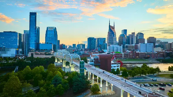 Günbatımında Nashville ufuk çizgisi. Simgesel ATT Binası ve Cumberland Nehri üzerindeki John Seigenthaler yaya köprüsü. Havadan bakıldığında şehrin modern cazibesi ve doğal güzelliği görülüyor..